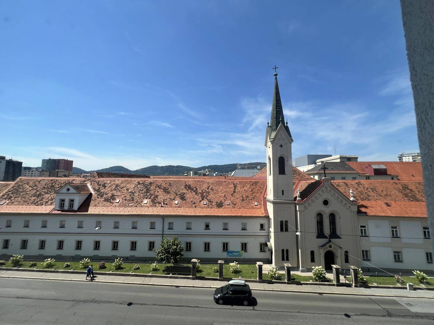 Blick aus dem Fenster auf eine Kirche und umliegende Gebäude unter blauem Himmel.