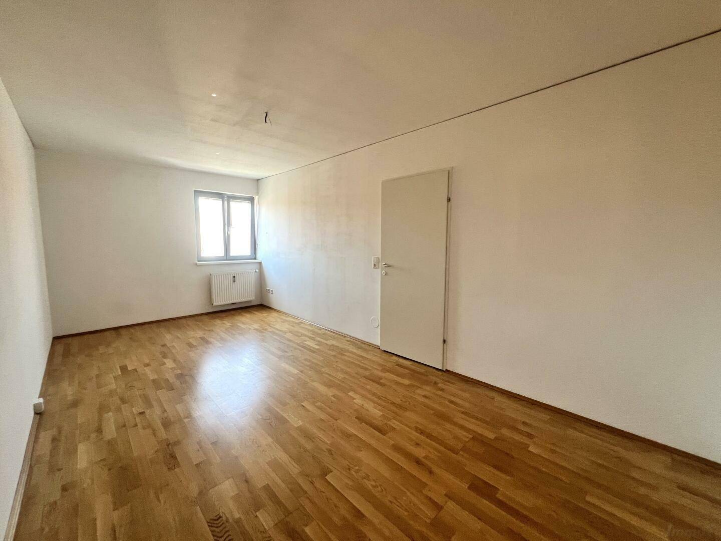 Helles Zimmer mit Parkettboden und einem Fenster, ideal als Schlaf- oder Arbeitszimmer nutzbar.