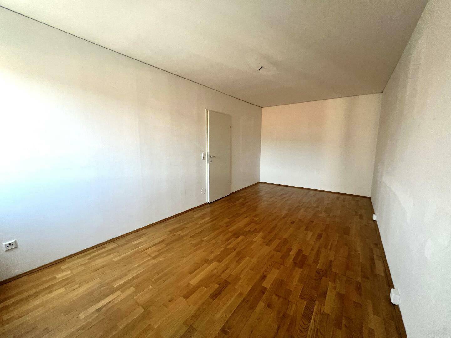 Geräumiges Zimmer mit Parkettboden und weiß gestrichenen Wänden, vielseitig nutzbar.