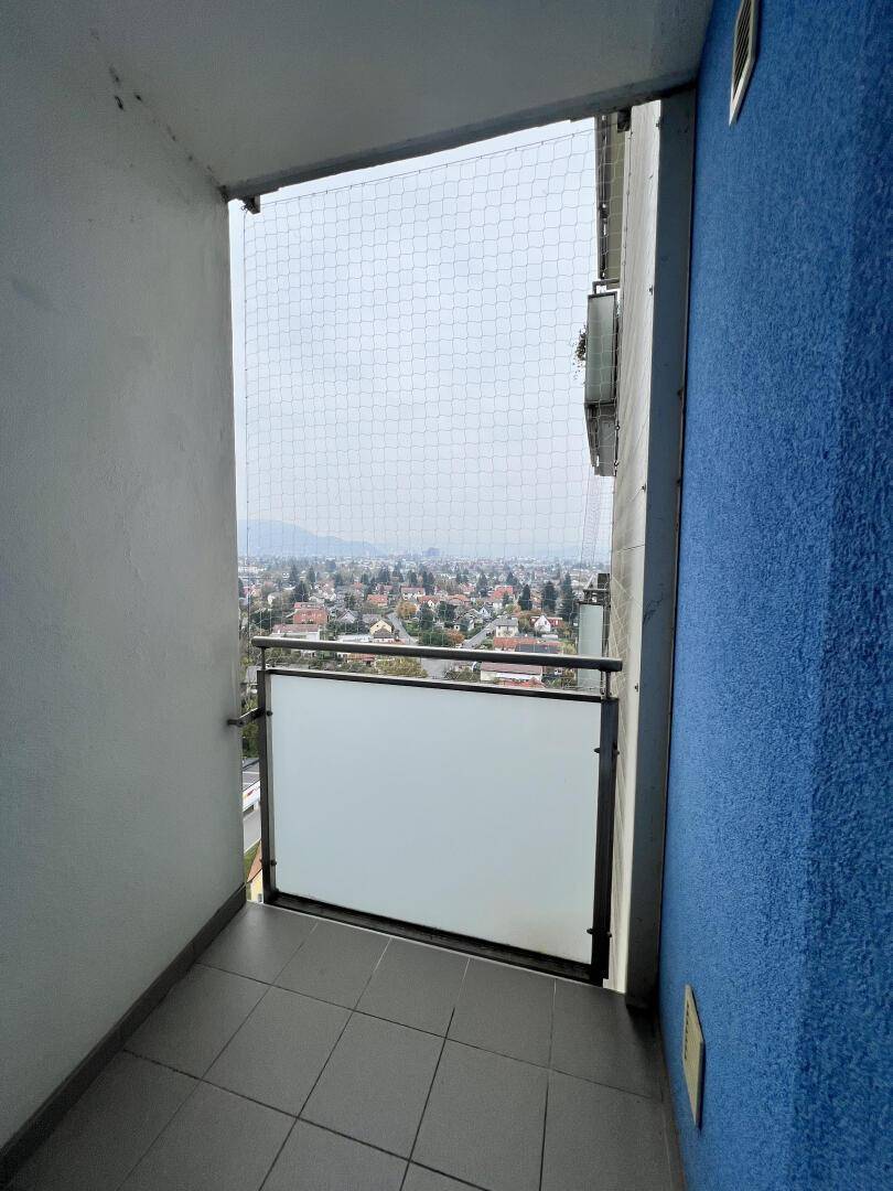 Schmaler Balkon mit Fliesenboden und weitem Blick über die Stadt und die Umgebung.