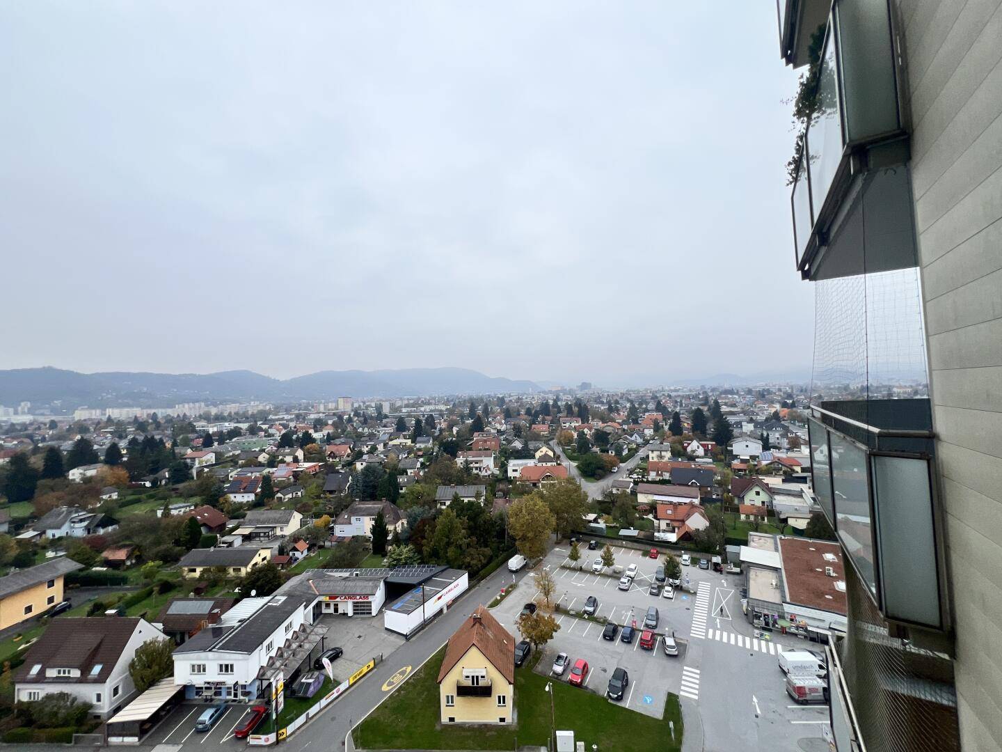 Weitläufiger Blick über die städtische Bebauung und die umliegende Landschaft mit Bergen im Hintergrund.