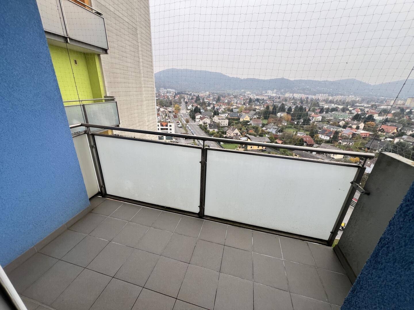 Balkon mit Fliesenboden und weitem Blick über die Stadt und die umliegenden Berge.
