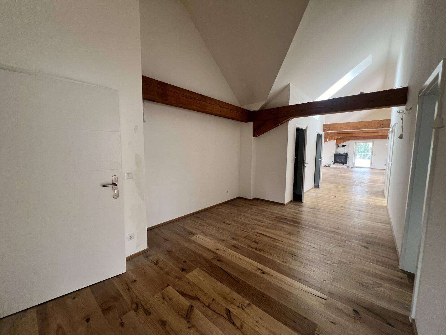 Heller Wohnbereich mit Eichenparkett, freiliegenden Holzbalken und Dachschrägen.