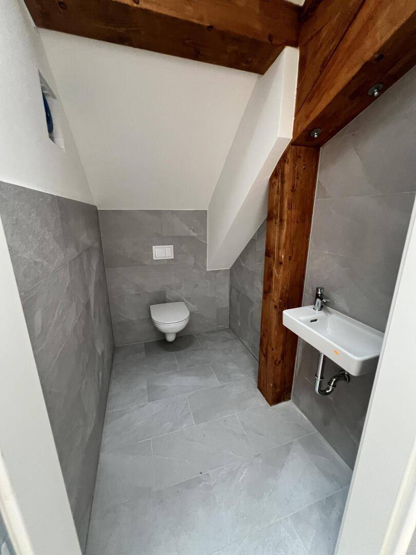 Kleines Gäste-WC mit modernen grauen Fliesen, Wand-WC und Waschbecken.