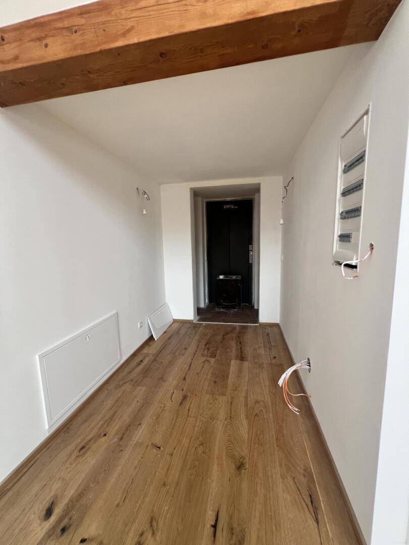 Heller Flur mit Holzboden und Zugang zu einem modernen Aufzug.