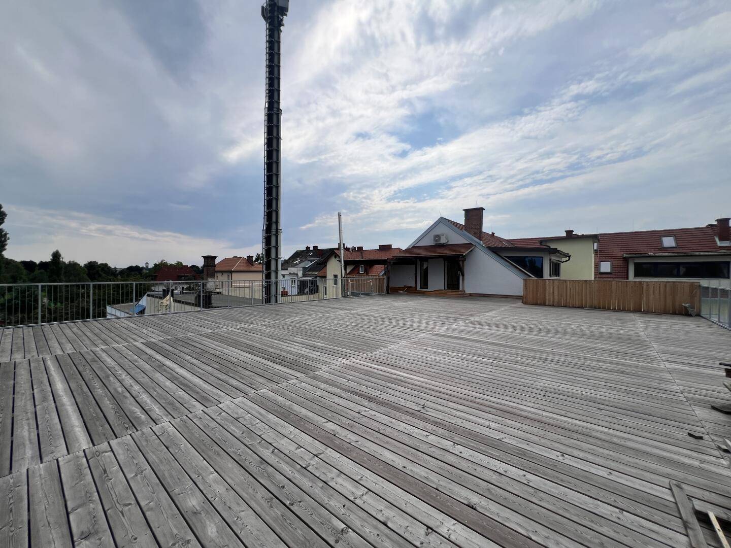 Weitläufige Holzterrasse mit Blick auf die Umgebung und einen Sendemast im Hintergrund.