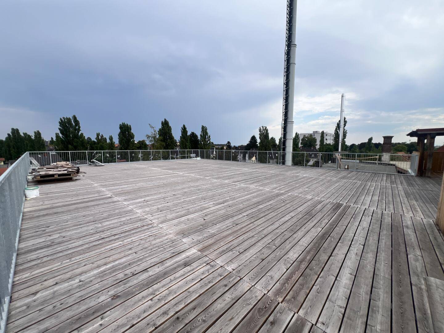 Große Holzterrasse mit Metallgeländer und Panoramablick über die Stadt.