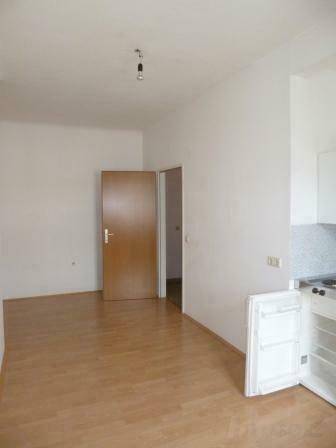 Geräumiger Wohnbereich mit hellem Laminatboden und Zugang zu weiteren Räumen.