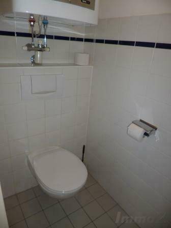 Separate Toilette mit Wand-WC und weiß gefliesten Wänden, funktional und sauber.
