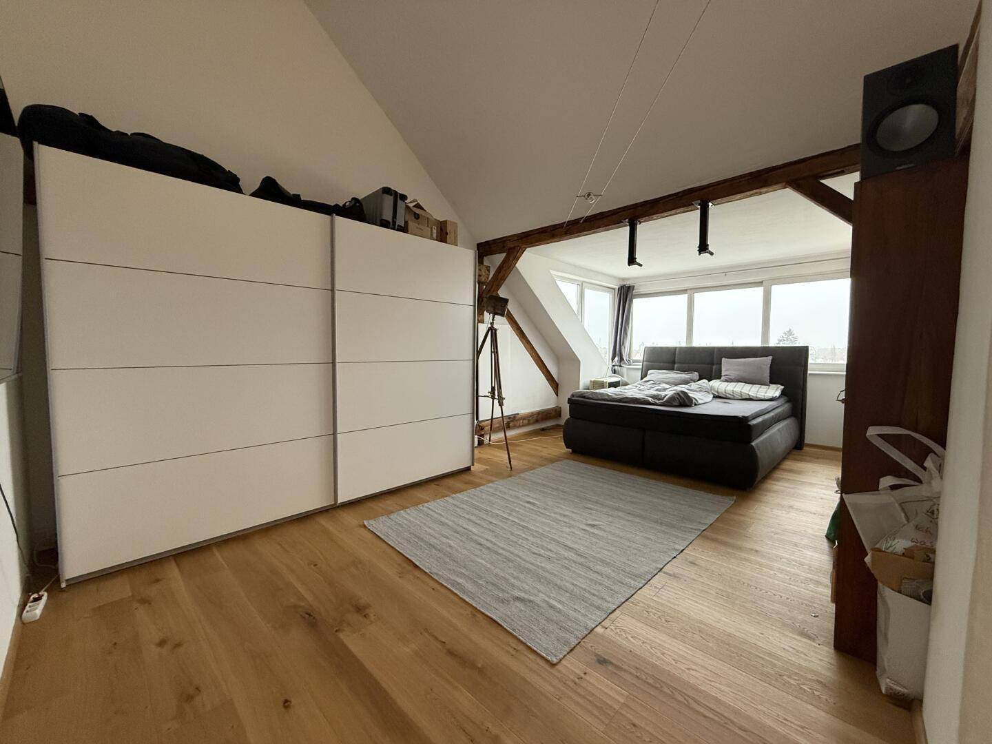 Schlafzimmer unter der Dachschräge mit großem Kleiderschrank, Holzboden und Dachfenster.