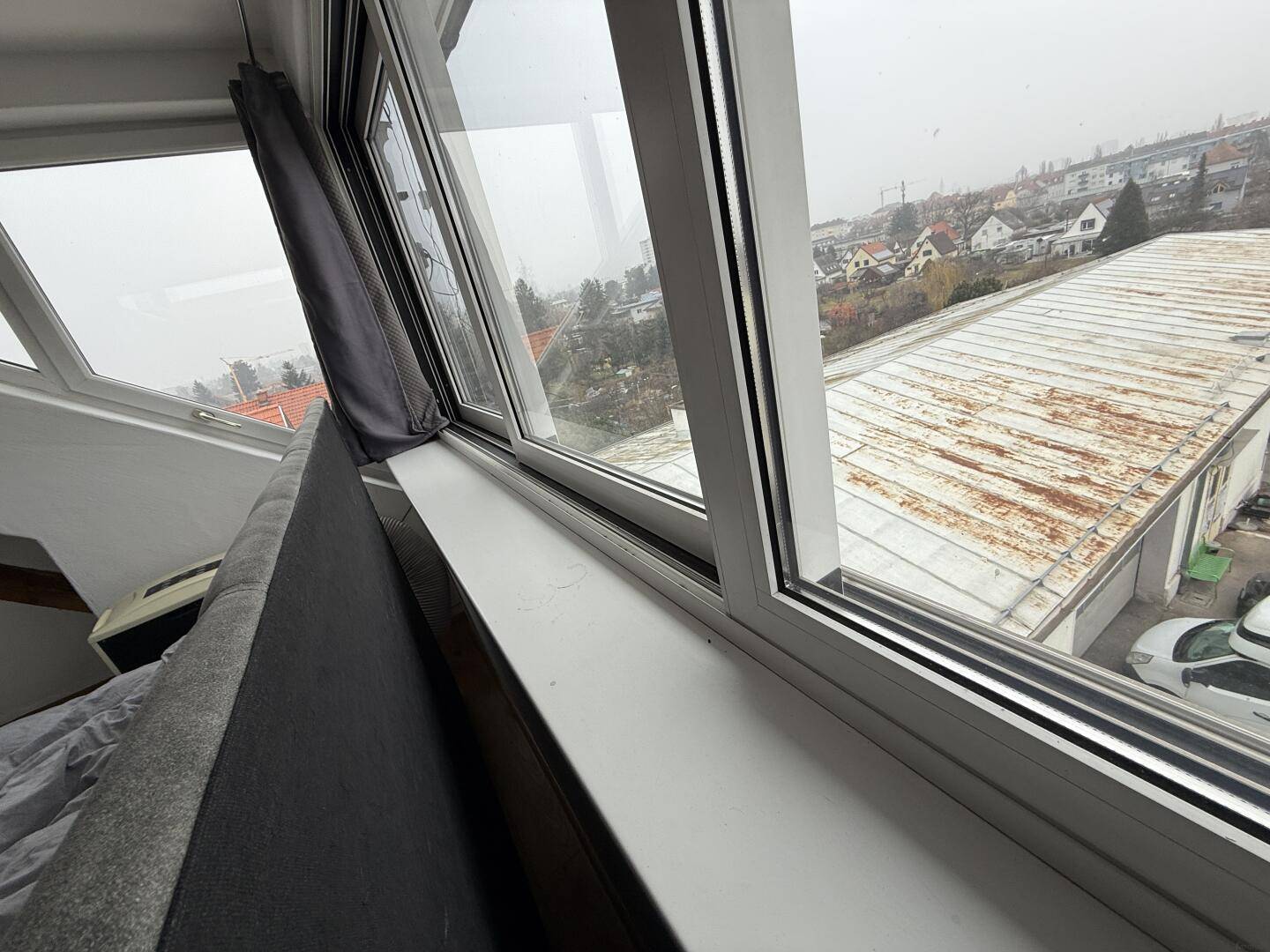 Blick aus dem Fenster des Schlafzimmers auf die Dächer und die städtische Umgebung.
