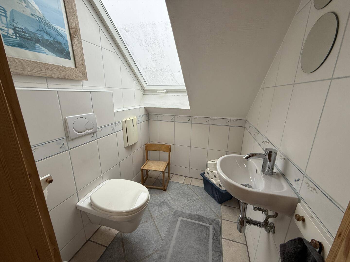 Kleines Gäste-WC mit Wand-WC, Waschbecken und einem Dachfenster für natürliches Licht.
