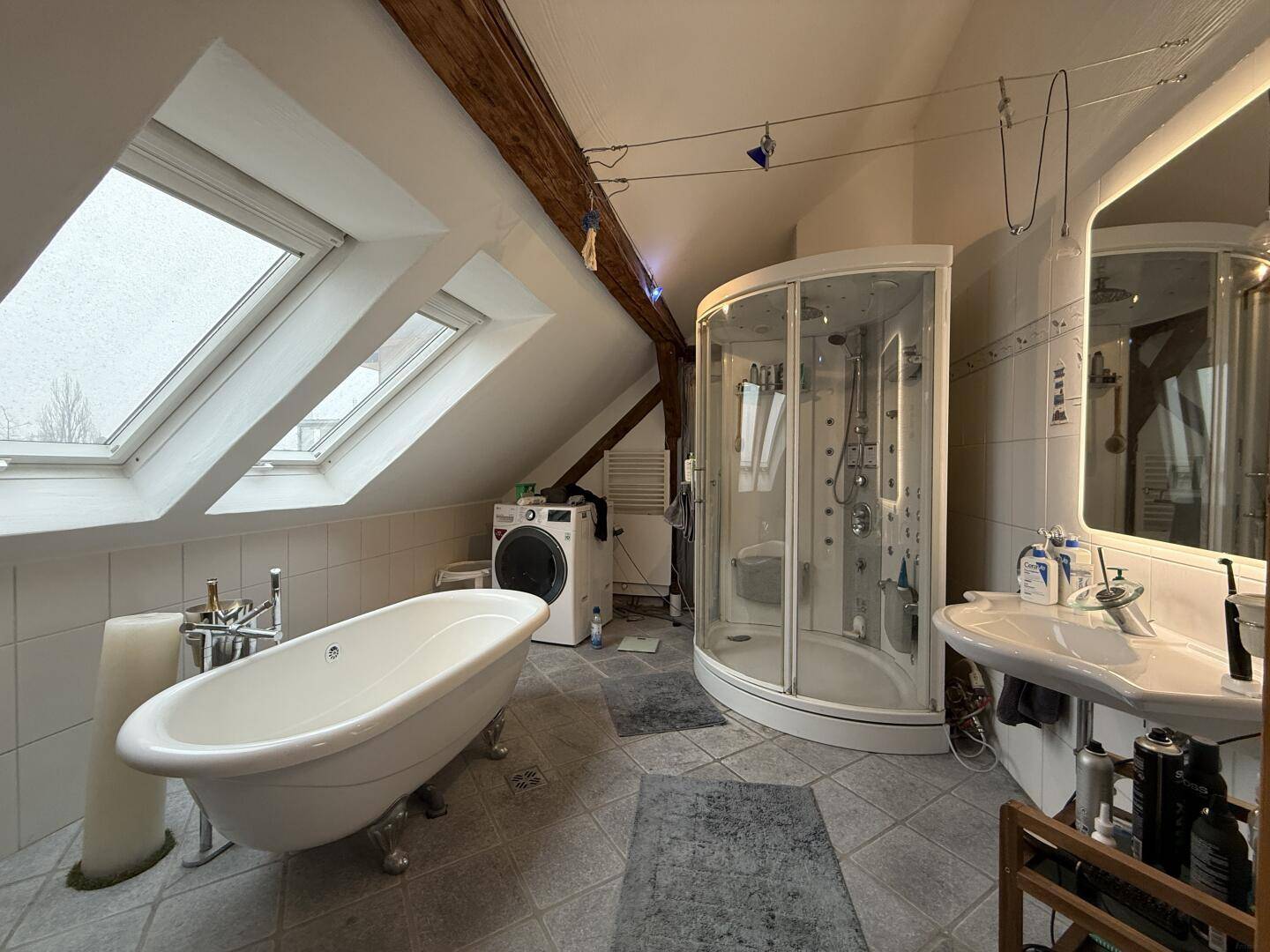 Geräumiges Badezimmer mit freistehender Badewanne, Duschkabine, Waschmaschine und Dachfenstern.