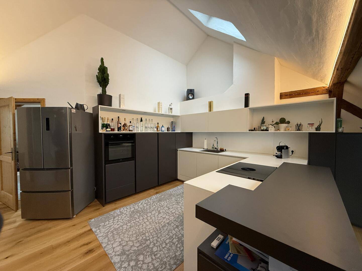 Moderne Küche mit integrierten Geräten, viel Stauraum und einem Dachfenster für natürliches Licht.