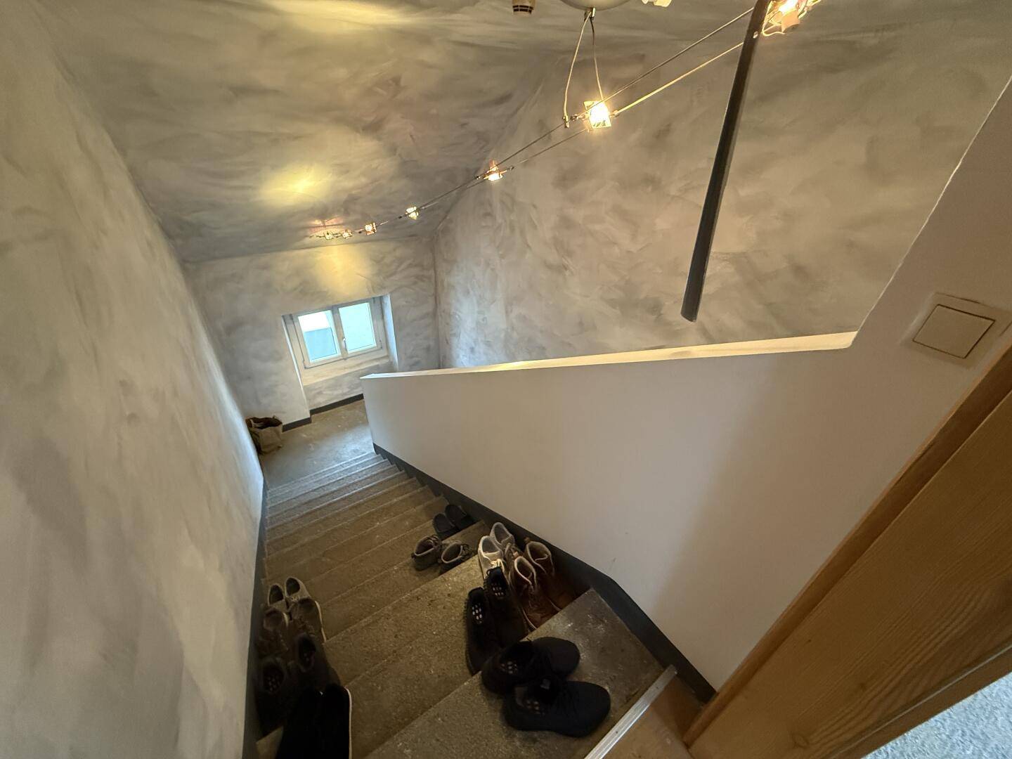 Blick von oben auf die Betontreppe mit strukturierten Wänden und einem kleinen Fenster.