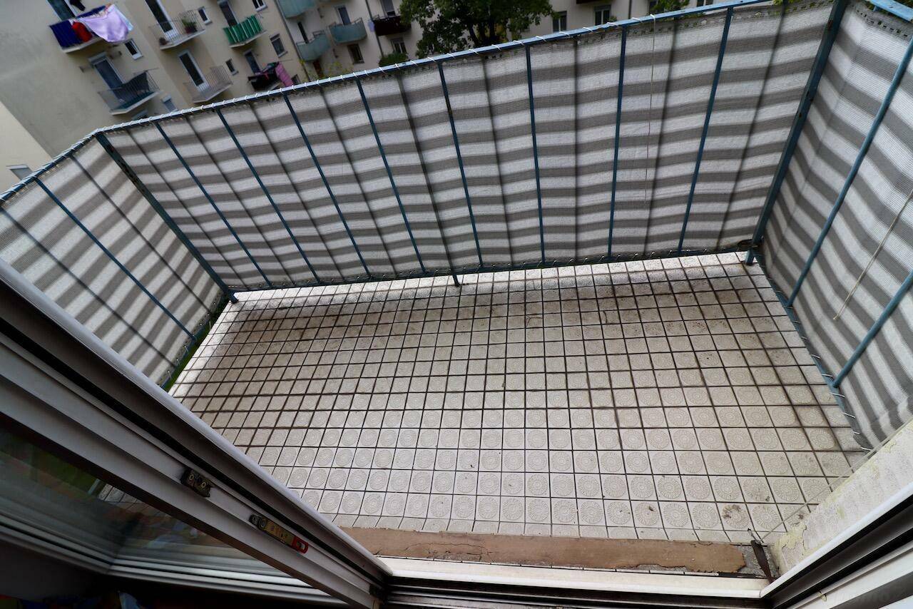 Gefliester Balkon mit Sichtschutz und Blick auf umliegende Gebäude.