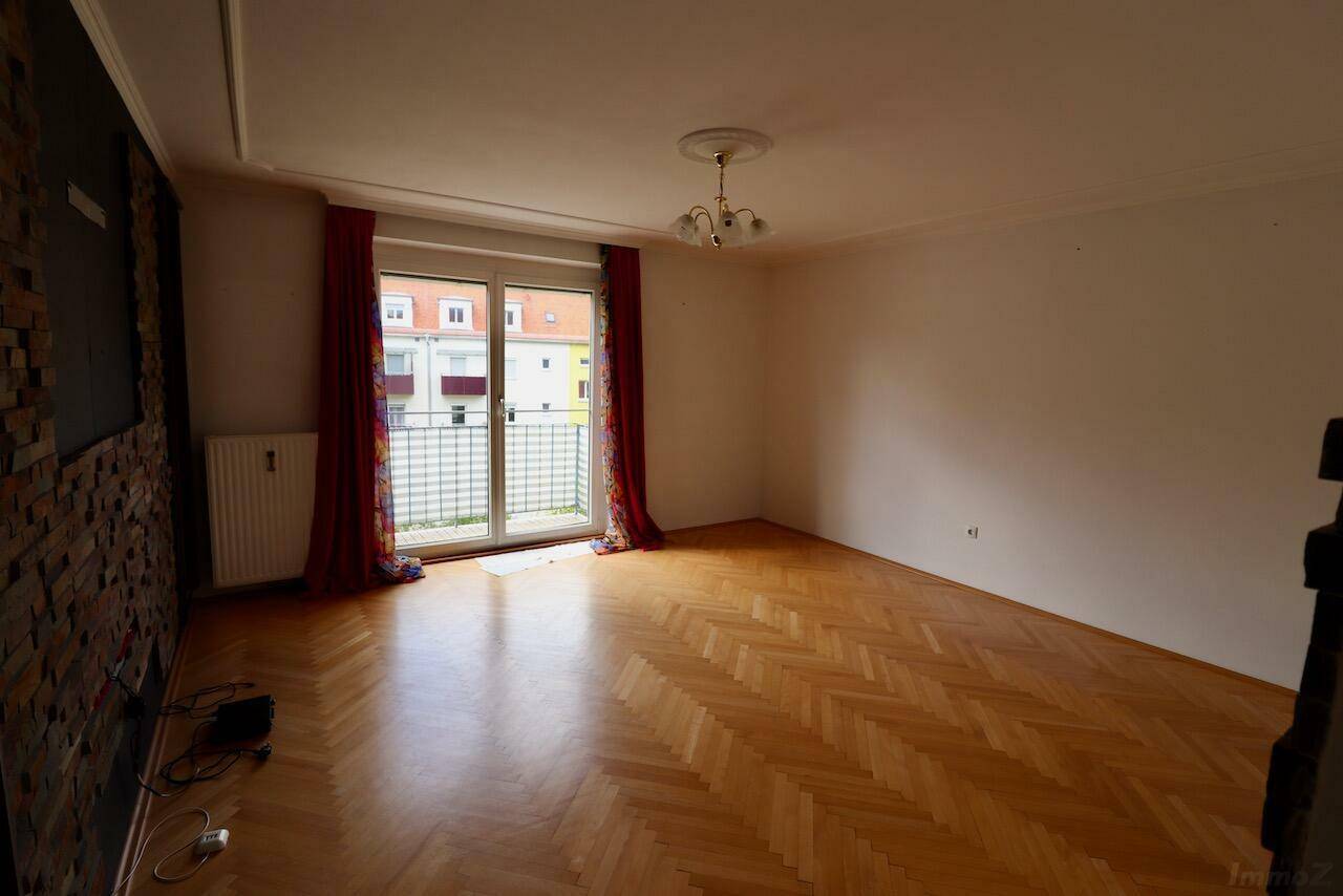 Helles Wohnzimmer mit Parkettboden, Balkonzugang und dekorativer Steinwand.