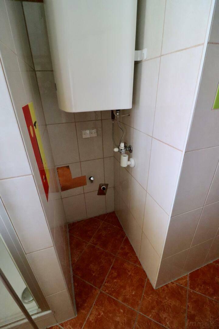 Badezimmer im Rohzustand mit Fliesenboden und Anschlüssen für Sanitäranlagen.