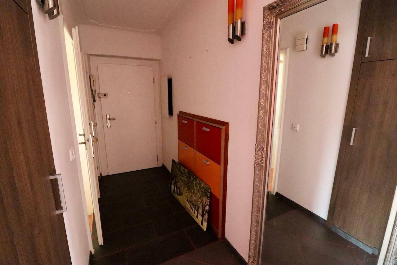 Eingangsbereich mit dunklem Fliesenboden, großem Spiegel und Schuhschrank.