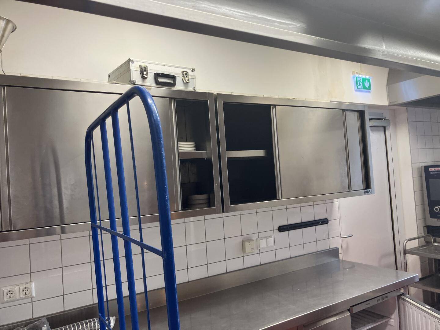 Edelstahlschränke und Arbeitsflächen in der professionellen Küche, mit weißen Fliesen an der Wand, hygienisch.
