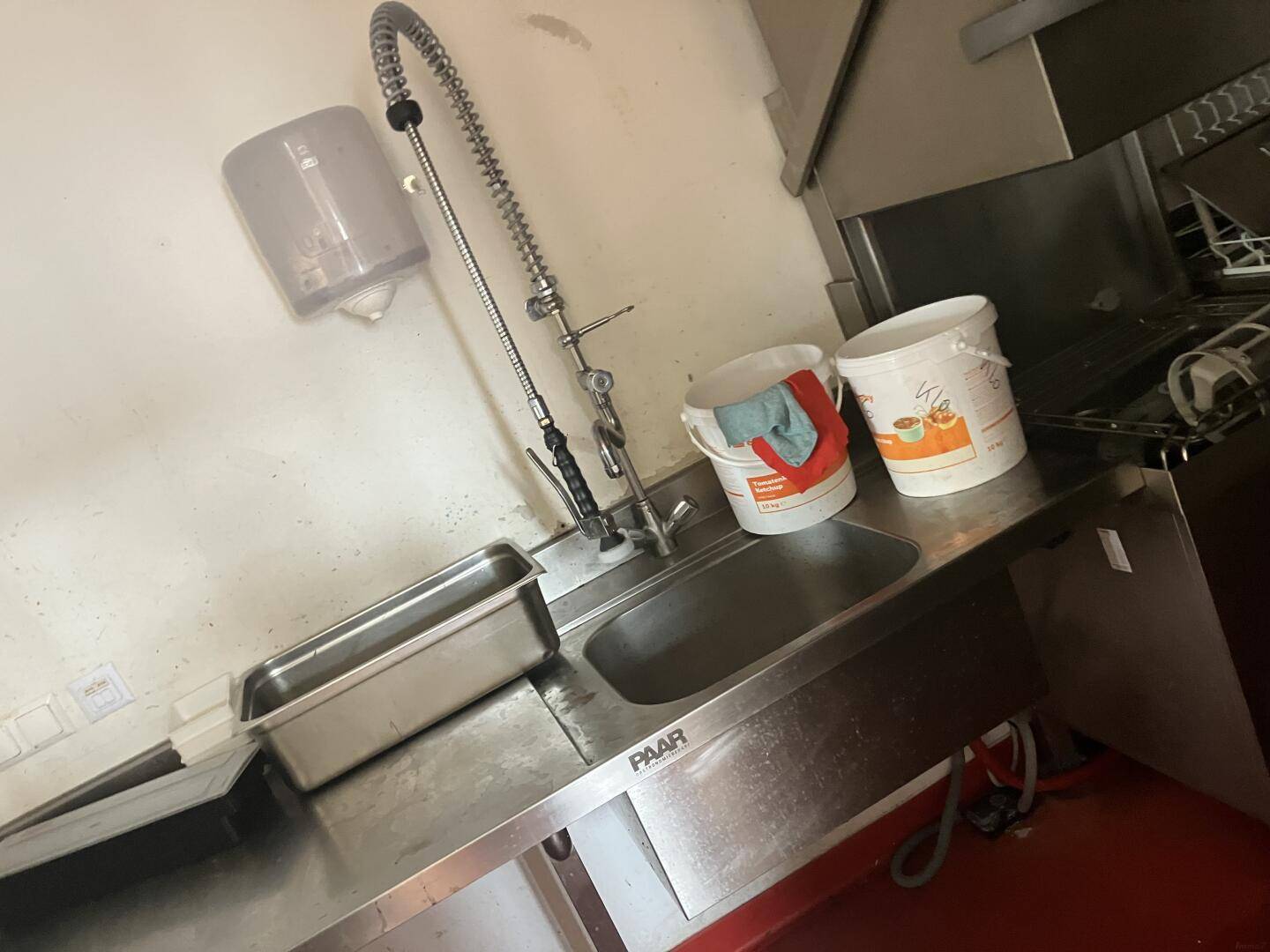 Spülbecken aus Edelstahl mit professioneller Armatur und Seifenspender in der Küche, hygienisch und funktional.