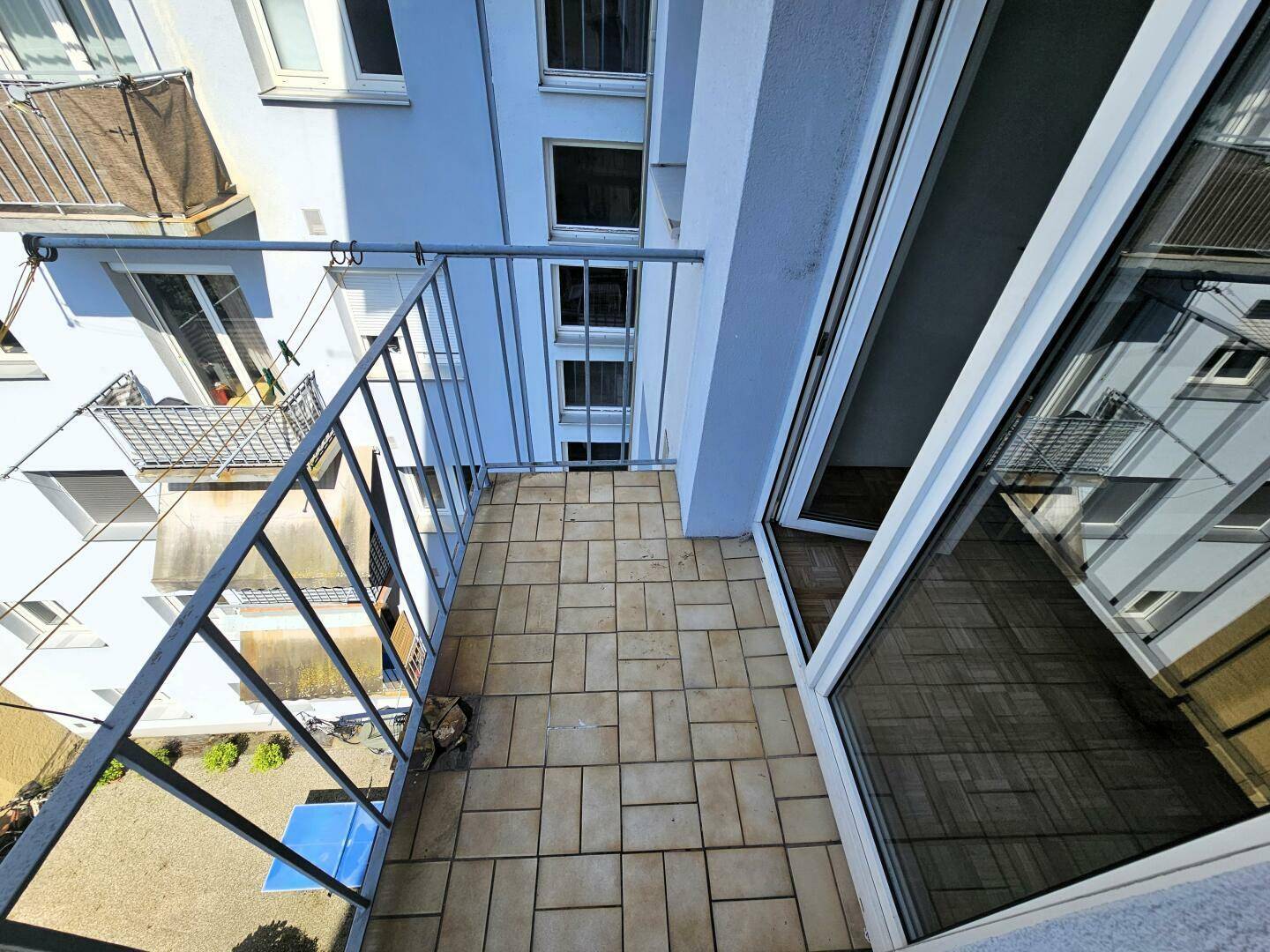 Balkon mit Fliesen und Metallgeländer, bietet eine Aussicht auf die Nachbarschaft.