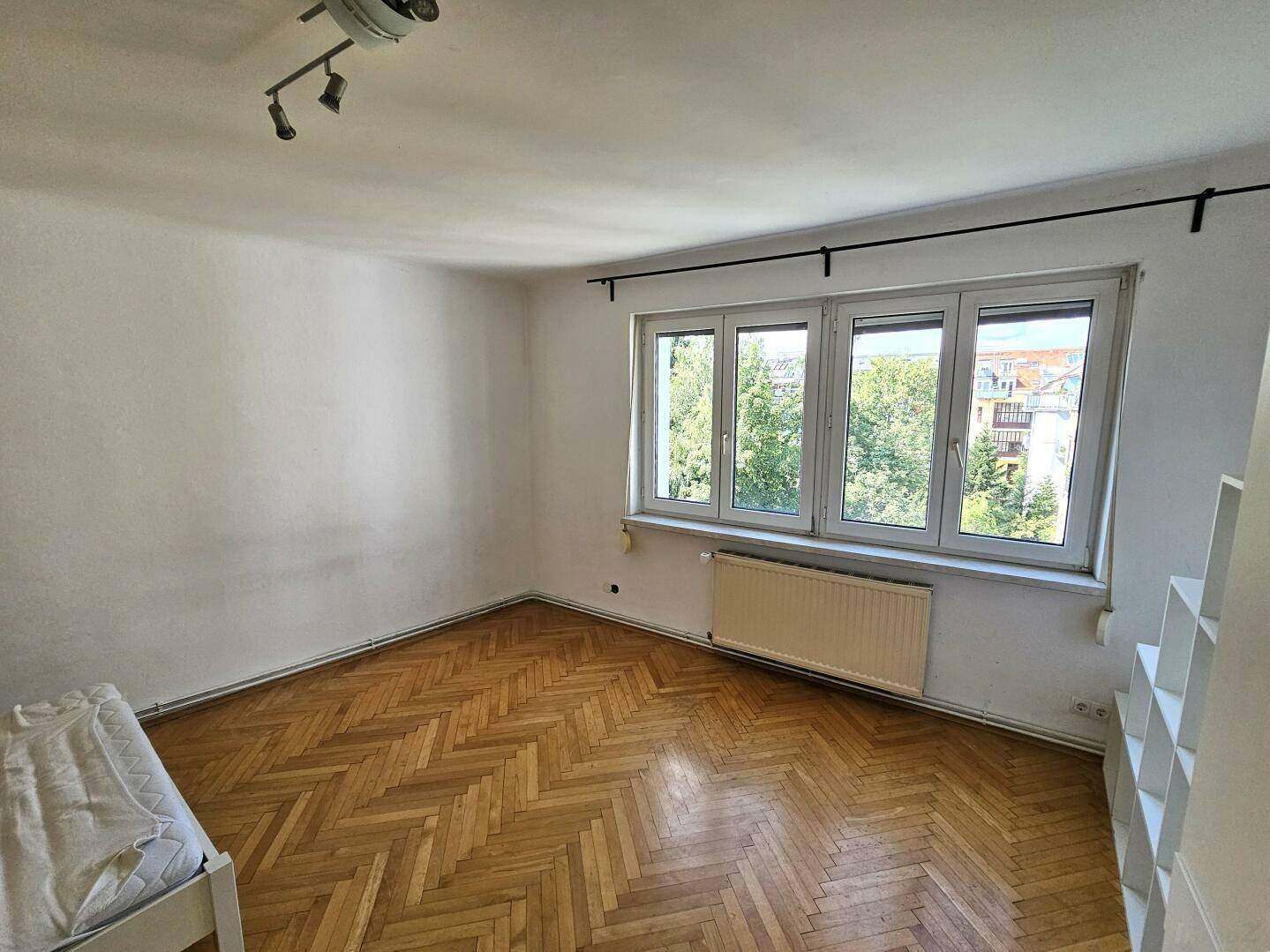 Geräumiges Schlafzimmer mit Parkettboden, großem Fenster und viel Tageslicht.