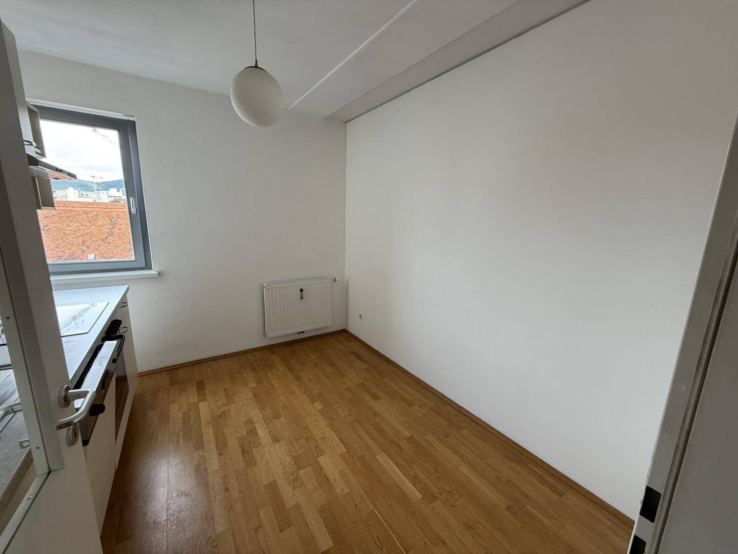 Küchenbereich mit Fenster, Heizkörper und Parkettboden, bereit für eine individuelle Gestaltung.