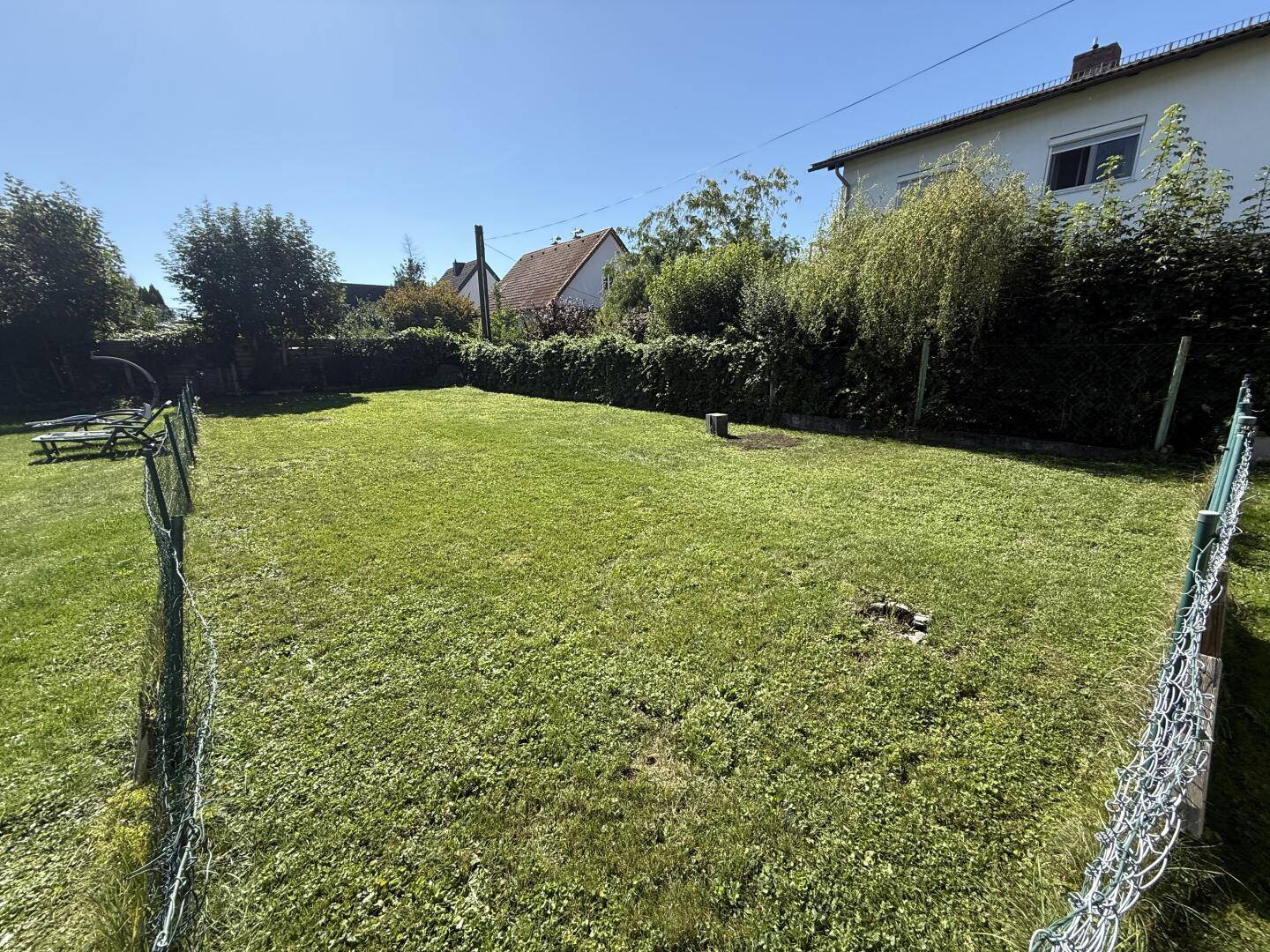 Großer, gepflegter Garten mit Rasenfläche und Hecke, ideal zum Entspannen im Freien.