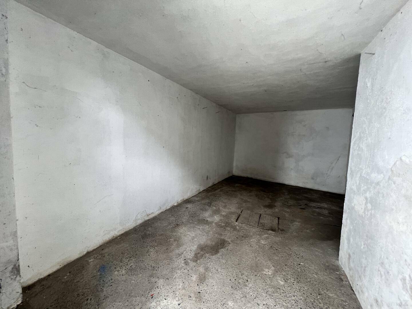 Leerer Abstellraum mit Betonwänden und -boden, ideal für Lagerzwecke.