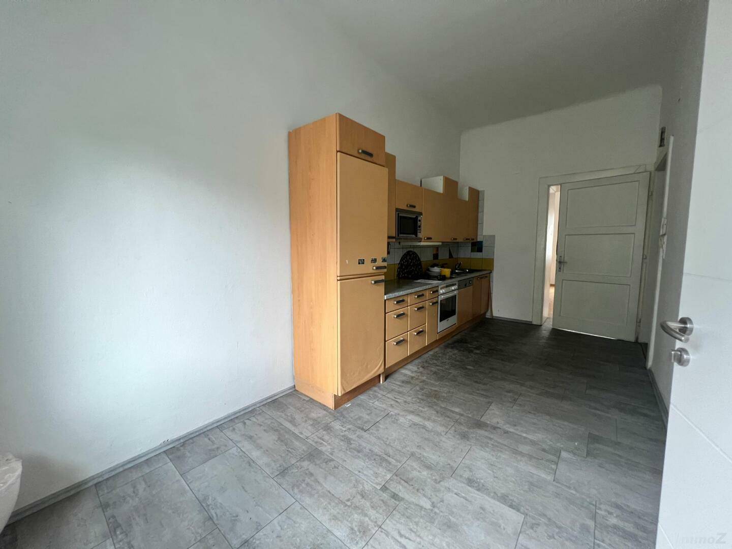 Geräumige Küche mit umfangreicher Schrankzeile, modernen Geräten und Fliesenboden.
