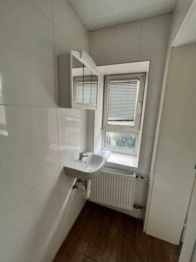 Badezimmer mit Waschbecken, Spiegelschrank und Fenster, das für natürliches Licht sorgt.
