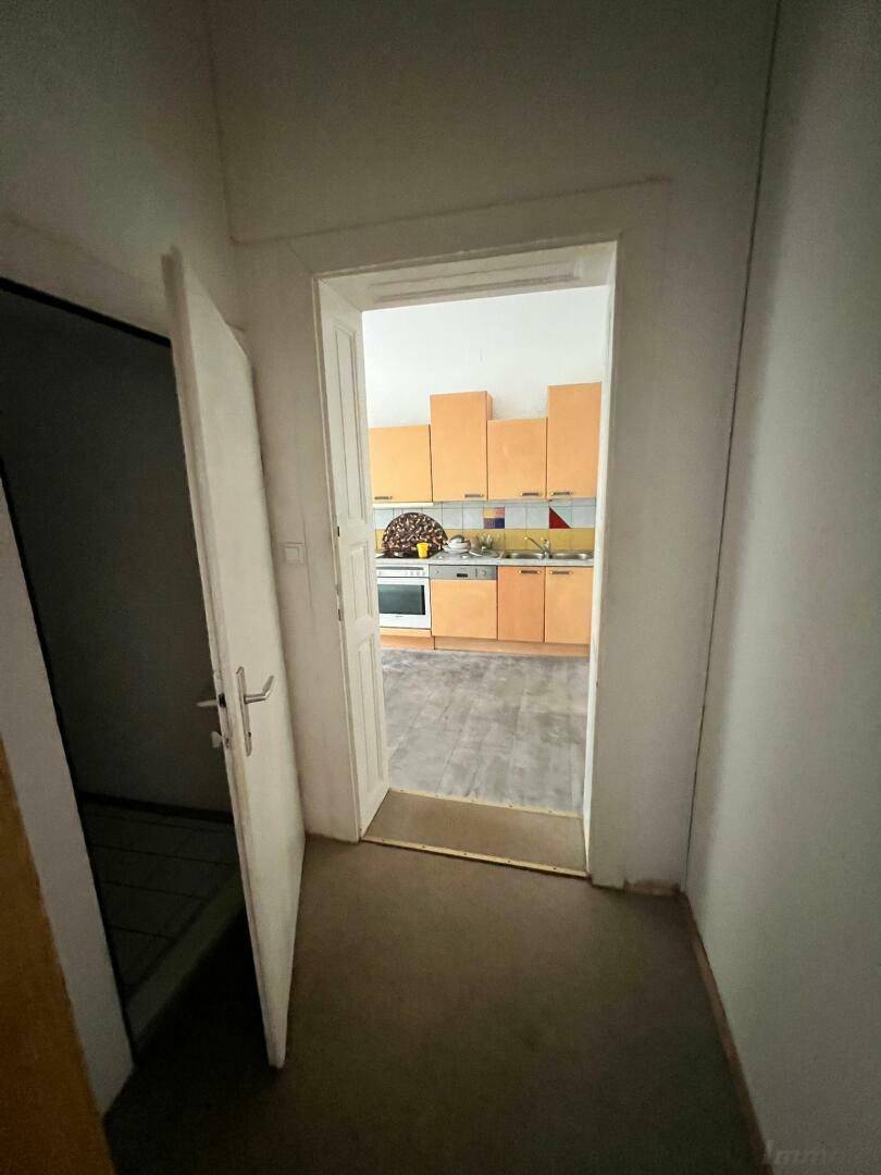 Flur mit Blick in die Küche, die mit hellbraunen Schränken ausgestattet ist.