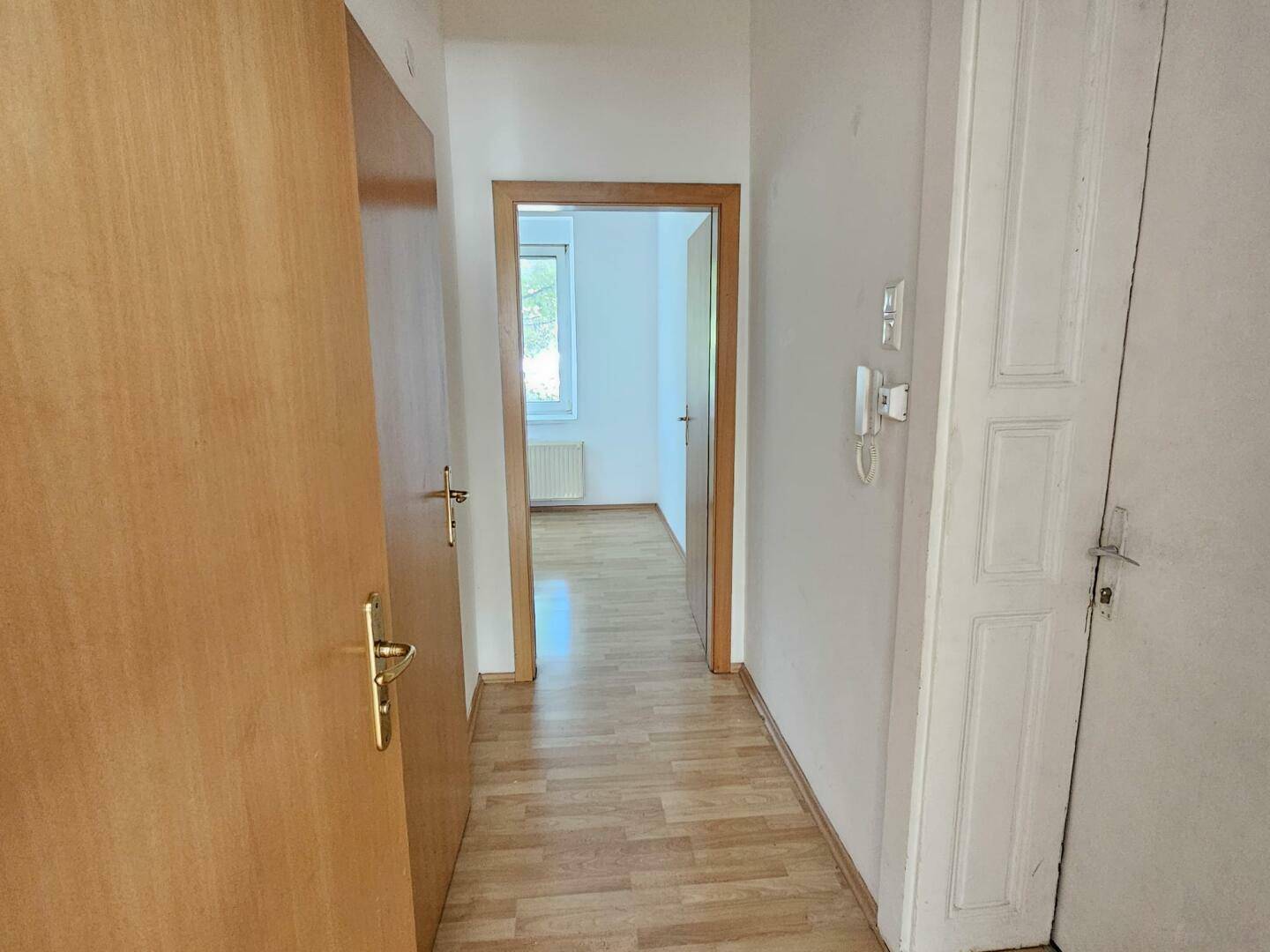 Langer Flur mit Holzböden und Türen, der die einzelnen Bereiche der Wohnung miteinander verbindet.