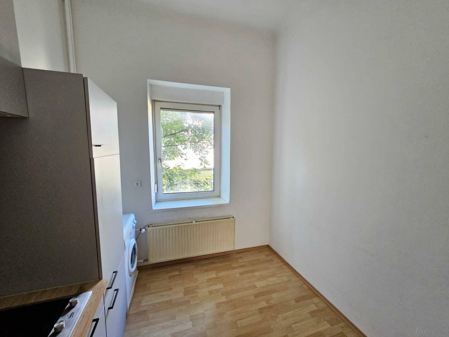 Heller Raum mit Fenster und Heizkörper, bietet Platz für eine kleine Essecke oder Arbeitsbereich.