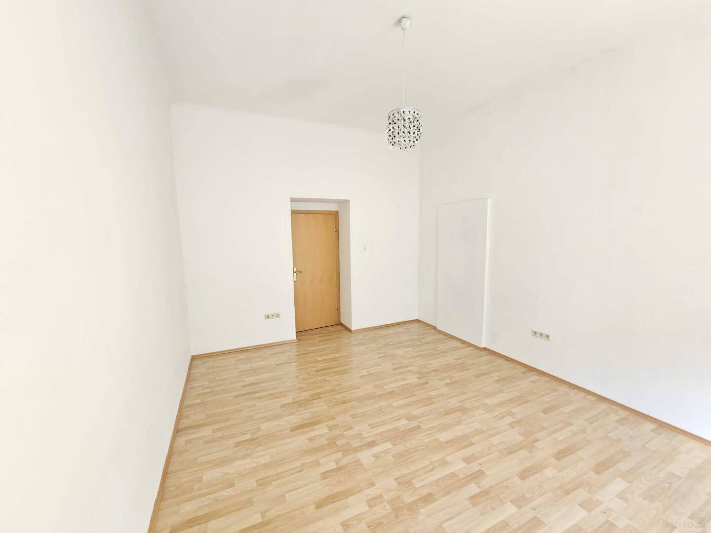 Freundliches Zimmer mit Holzboden und schlichten weißen Wänden, bietet vielseitige Nutzungsmöglichkeiten.