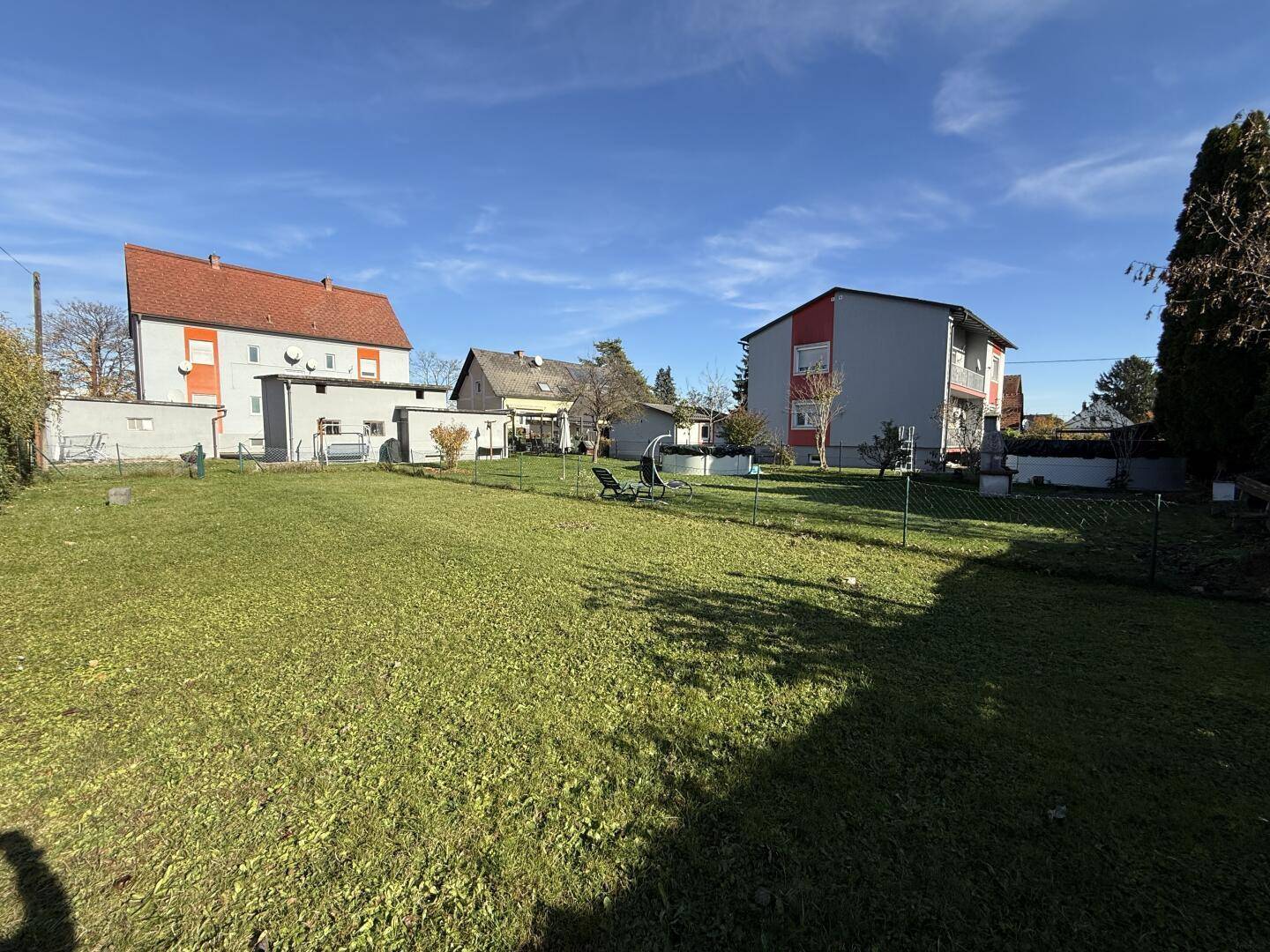 Weitläufige Rasenfläche im Garten mit Blick auf die umliegenden Häuser und viel Sonne.