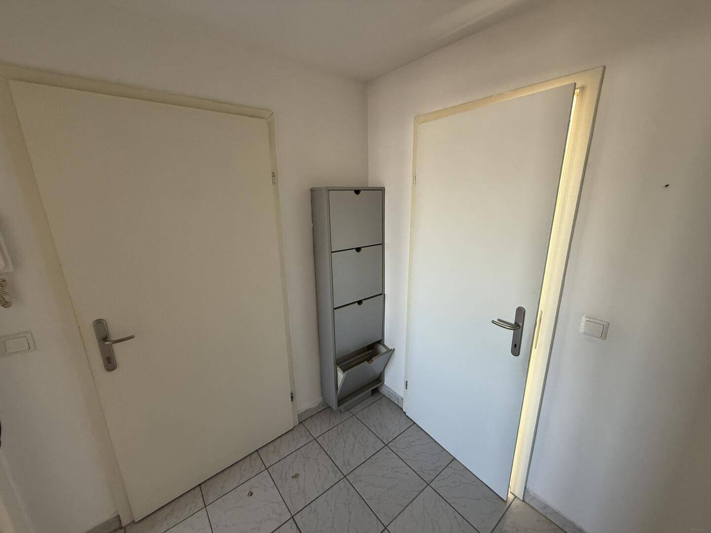Eingangsbereich mit Fliesenboden und praktischem Schuhschrank, der zu den Zimmern führt.