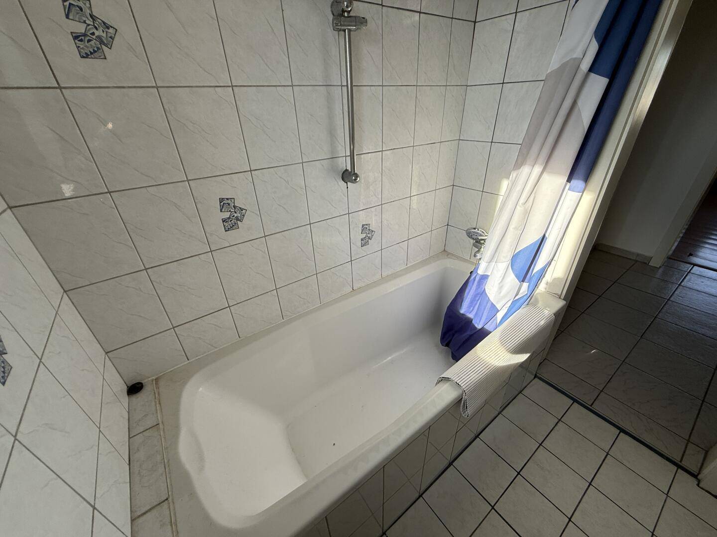 Badewanne mit Duschvorhang und weißen Fliesen, bereit für entspannende Momente.