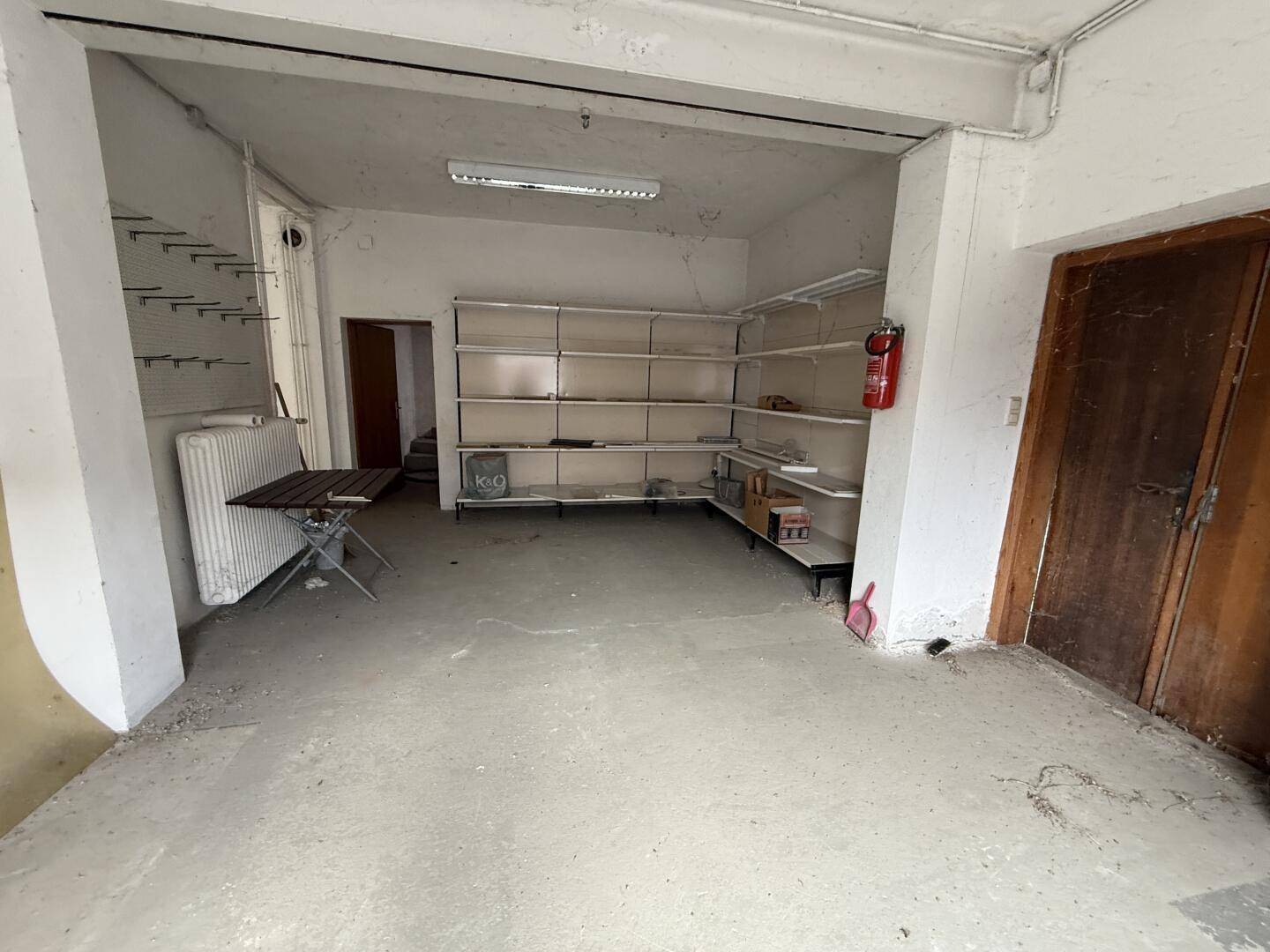 Lagerraum mit Betonboden, Regalsystemen und einem Feuerlöscher, bereit für die Nutzung.