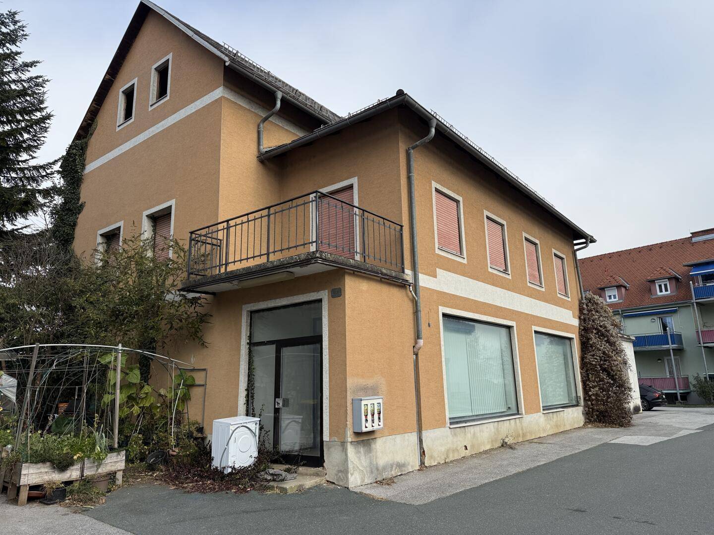 Fassadenansicht des Gebäudes mit mehreren Fenstern und einem Balkon, in einer städtischen Umgebung.