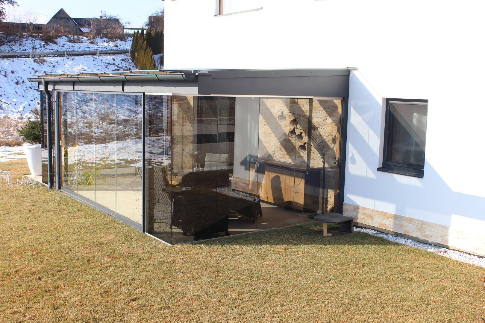 Nahaufnahme des modernen Wintergartens mit Glasfront und Zugang zum Gartenbereich.