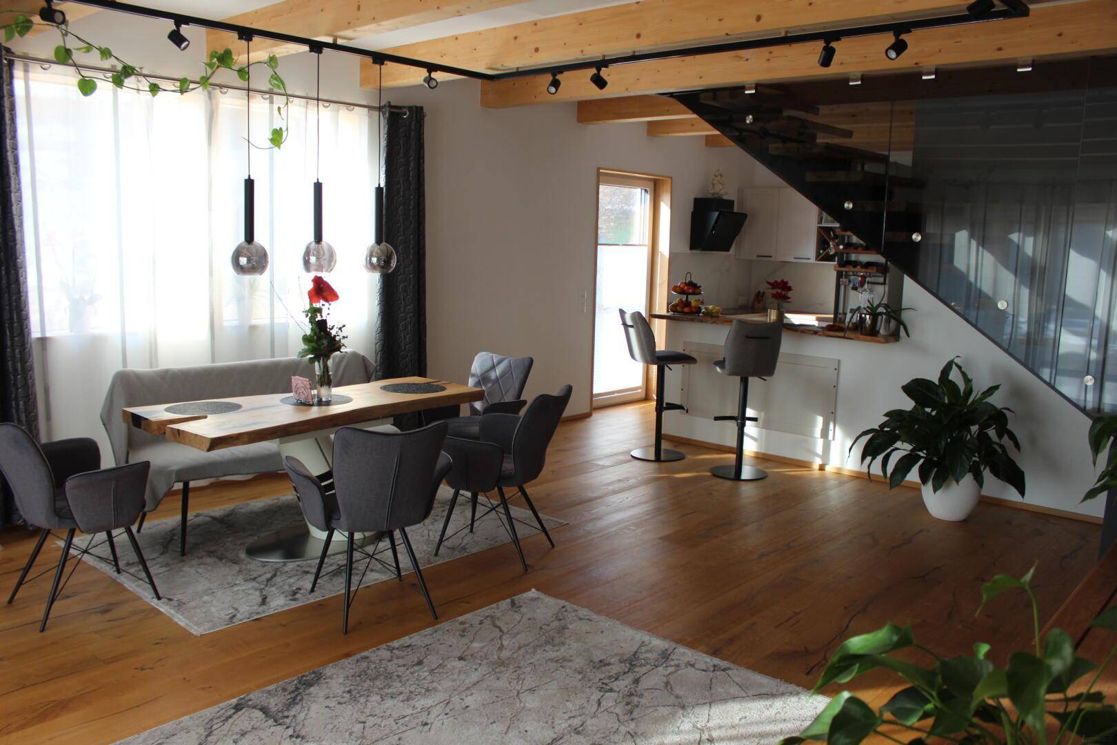 Lichtdurchfluteter Essbereich mit Holzboden und offener Küche, ideal für geselliges Beisammensein.