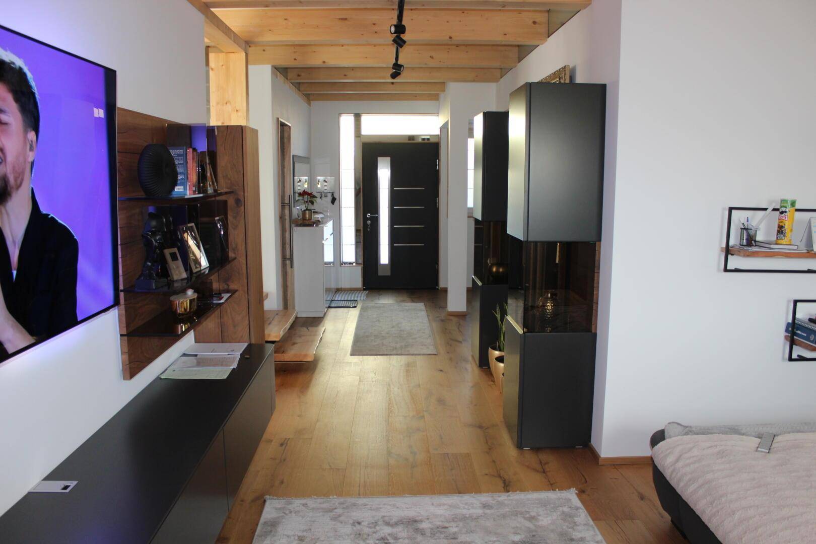 Heller Eingangsbereich mit Holzboden, offener Deckenkonstruktion und moderner Einrichtung.