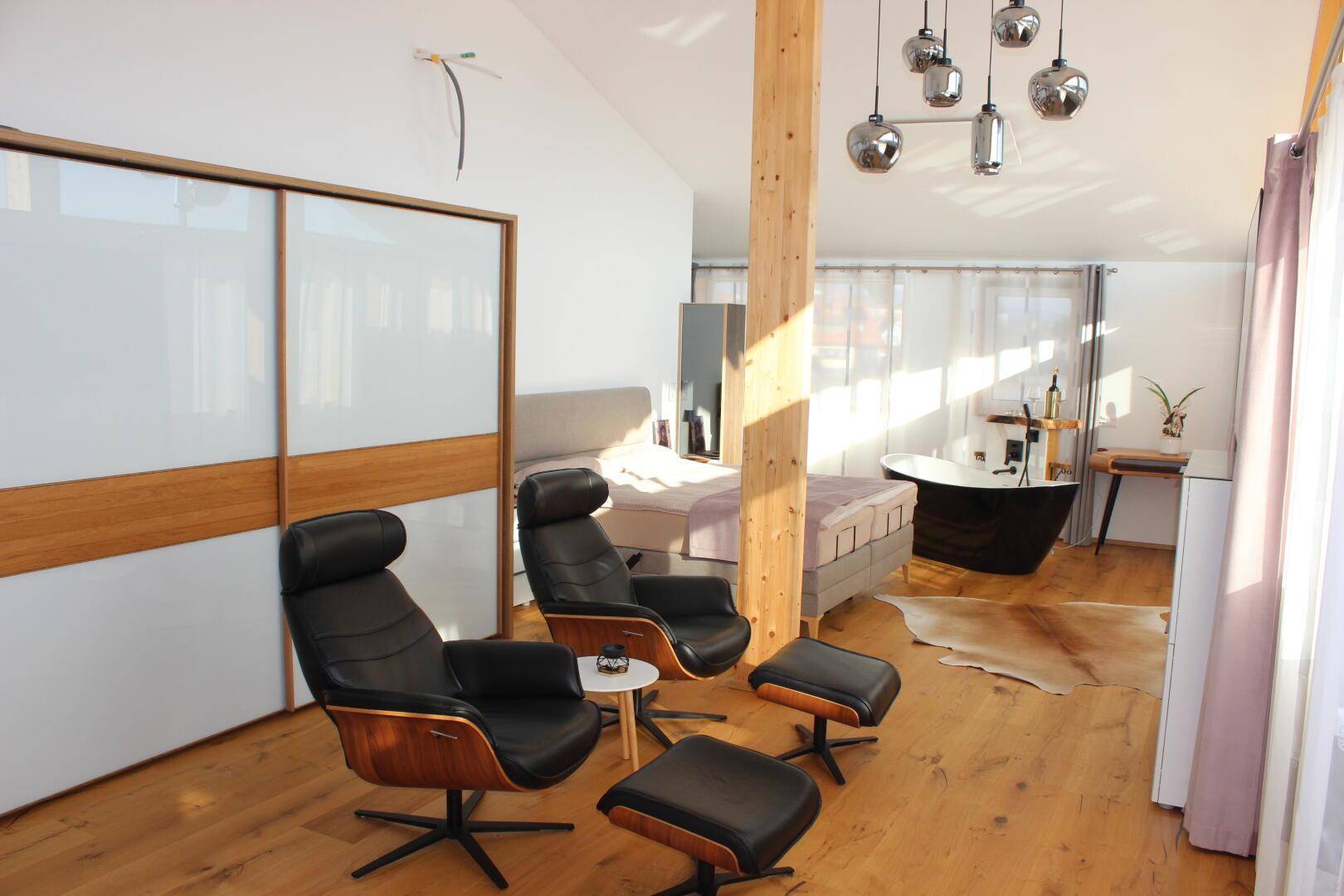 Luxuriöses Schlafzimmer mit freistehender Badewanne, Holzboden und Schiebetürenschrank.