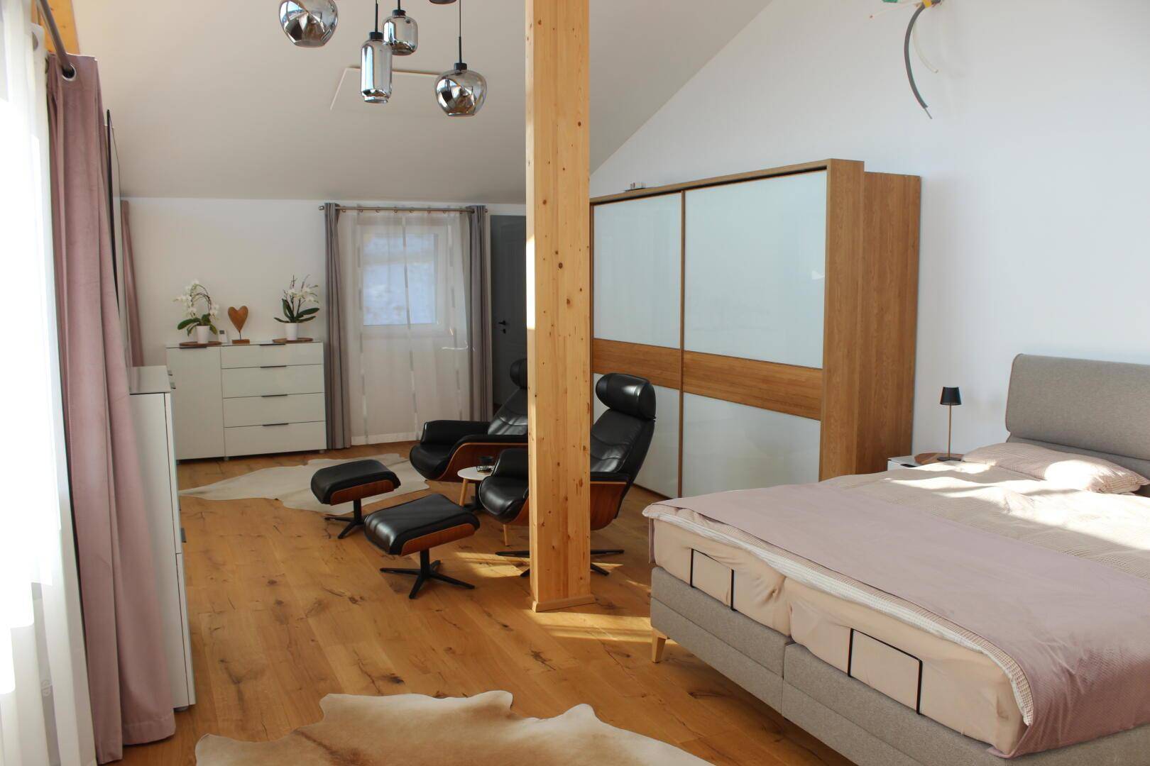 Helles Schlafzimmer mit Doppelbett, bequemen Sesseln und großem Schiebetürenschrank.