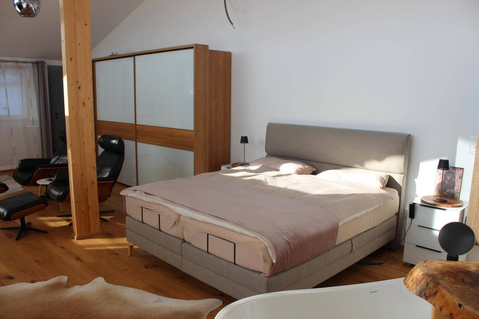 Geräumiges Schlafzimmer mit Doppelbett, großem Schiebetürenschrank und Holzboden.