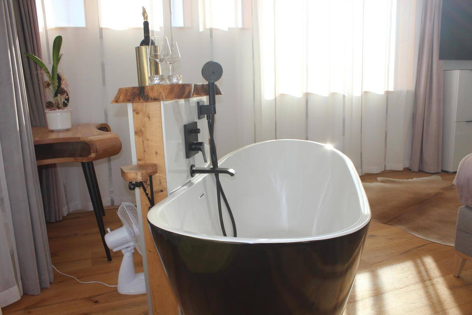Nahaufnahme der modernen freistehenden Badewanne mit schwarzer Armatur im Schlafzimmer.