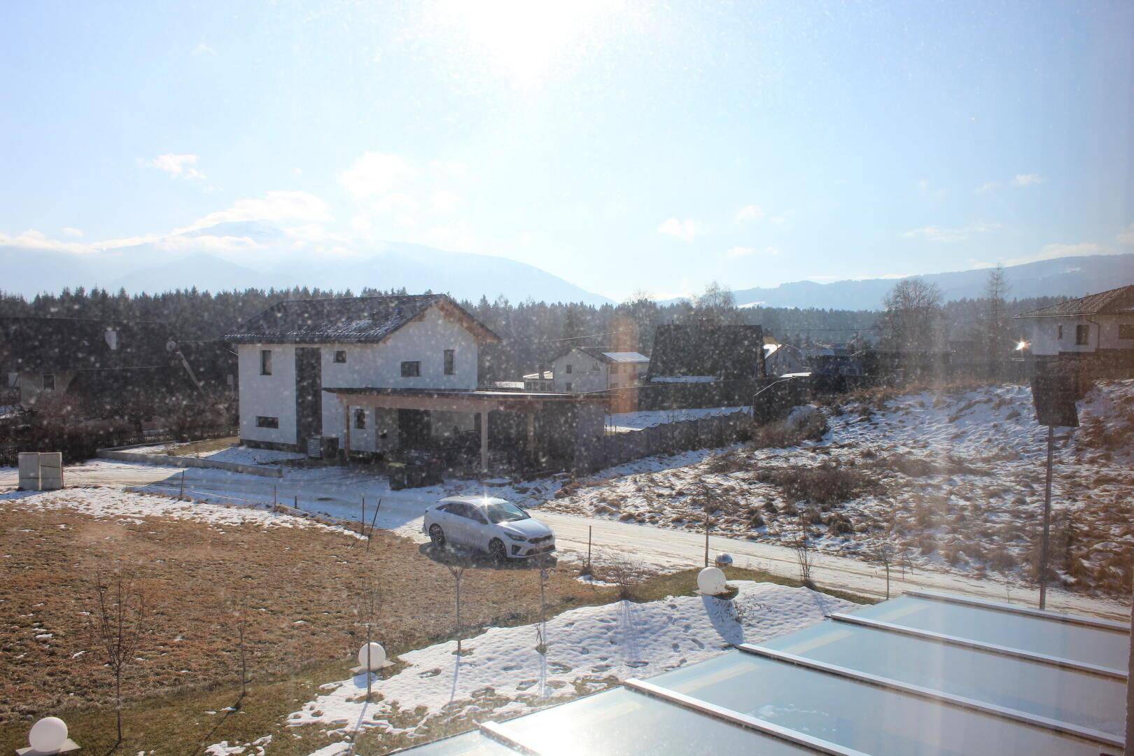 Weitläufiger Blick auf die verschneite Landschaft und umliegende Häuser von einem oberen Stockwerk.