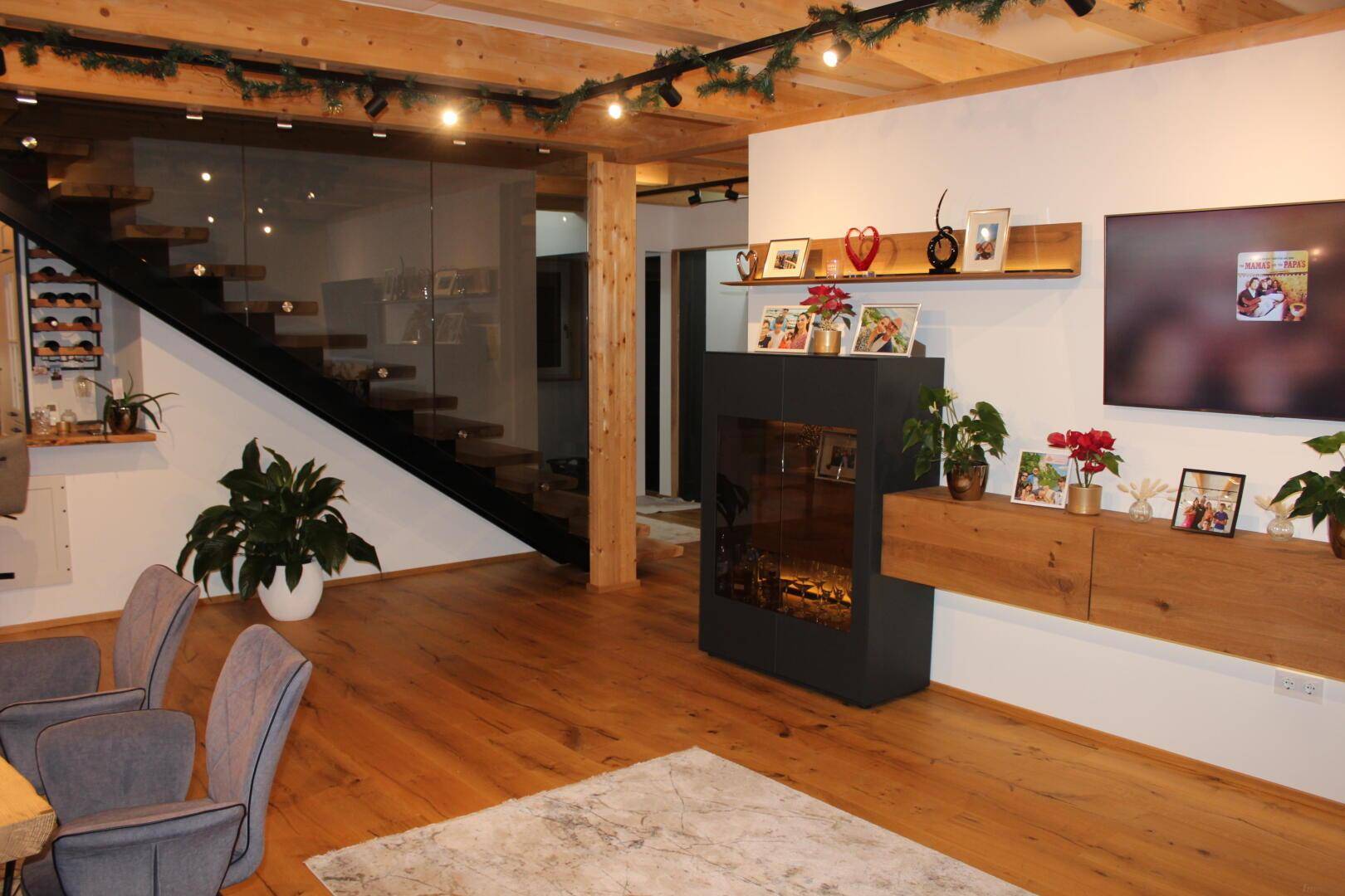 Geräumiges Wohnzimmer mit offener Treppe, Holzboden und stilvoller Dekoration unter Holzbalken.